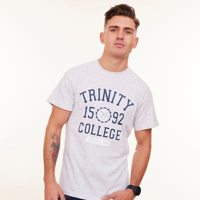 Man wearing a white t-shirt with 'Trinity 1592 College Dublin' text on a plain background